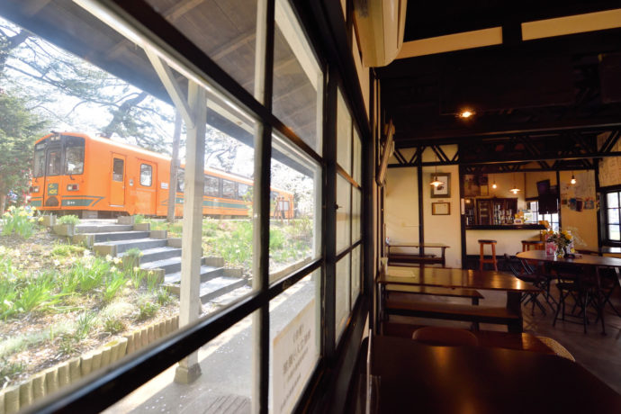 「赤い屋根の喫茶店 駅舎」の店内風景と映り込む津軽鉄道の電車