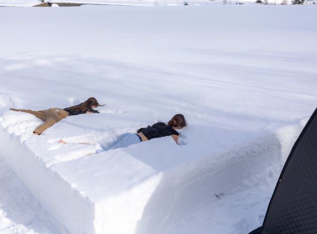 サウナ後雪の中にダイブして体を整える女性の写真