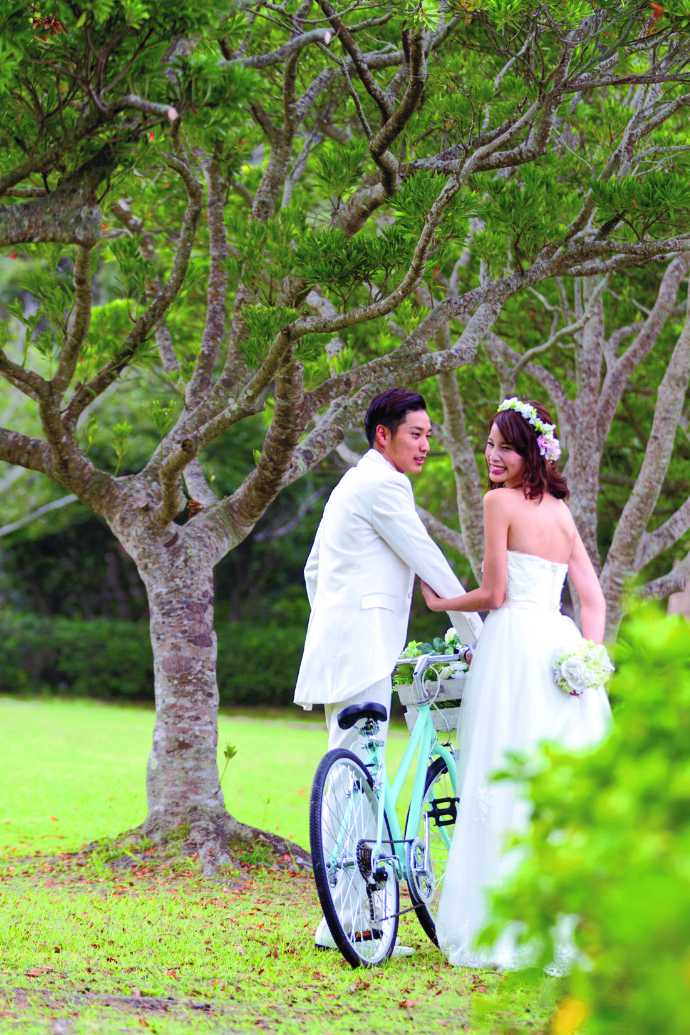 「沖縄ウェディングオンライン」の、森林で自転車と一緒に撮影したウエディングフォト