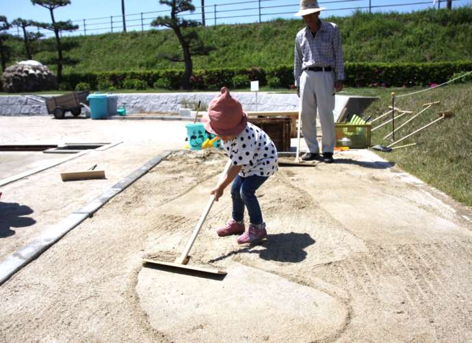 愛知県西尾市にある「西尾市塩田体験館 吉良饗庭塩の里」で昔の道具を使って塩田作業をする女の子