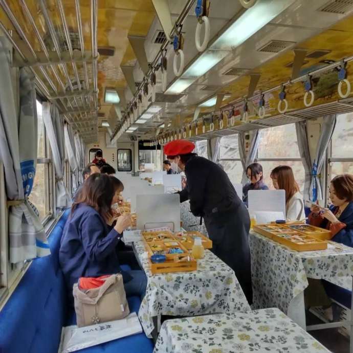 明知鉄道の食堂車車両内で食事をする乗客とアテンダント