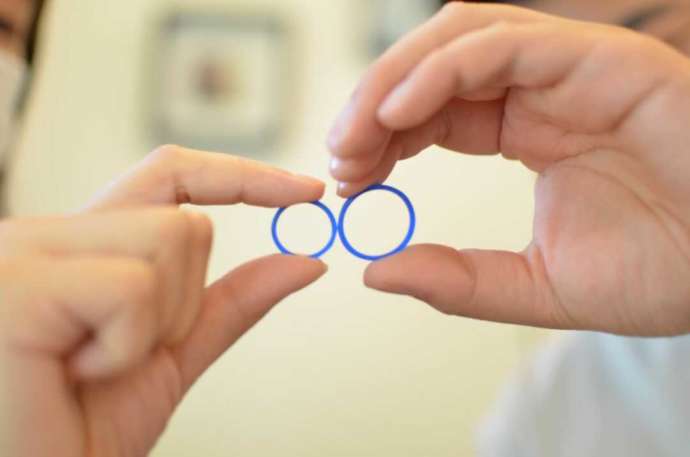 WAXで作った指輪を並べて持つカップルの手
