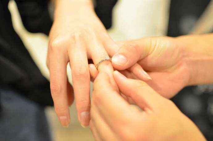婚約指輪を女性の指にはめる男性の手