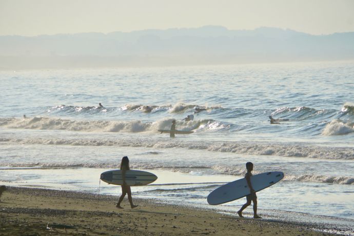 茅ヶ崎市の海岸でサーフボードを抱えて歩くサーファーたちの姿