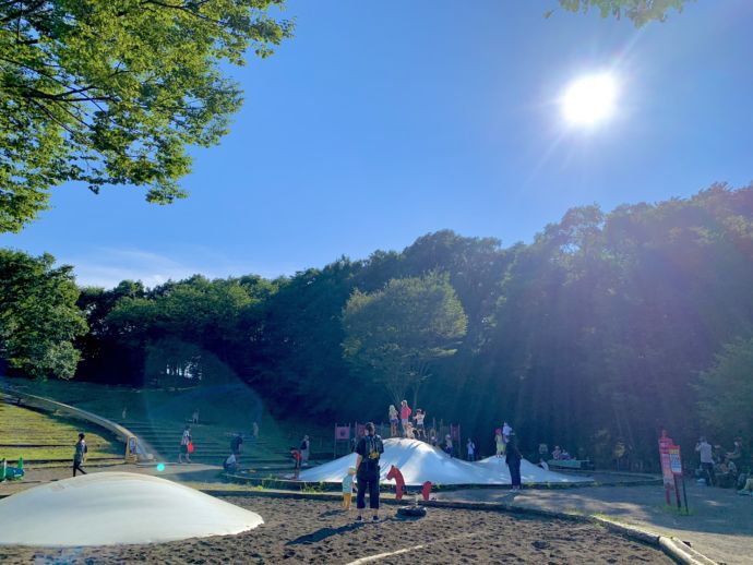 茅ケ崎里山公園の遊具で楽しむ子どもたちと、それを見守る家族の図
