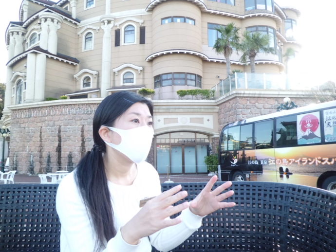 江の島ホテル本館を背景に話をする営業兼広報の石沢さん
