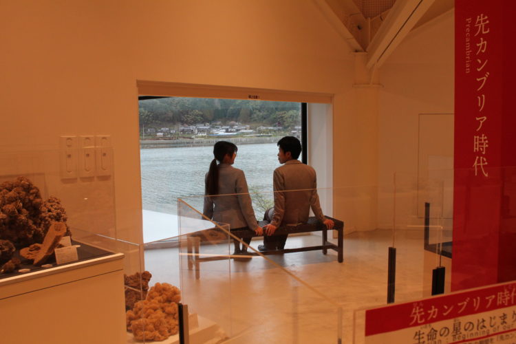 玄武洞ミュージアムの窓から円山川を眺める男女