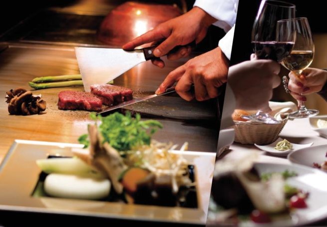 鉄板の上でステーキを焼くコックの手元とワインで乾杯する人の手元を映した写真