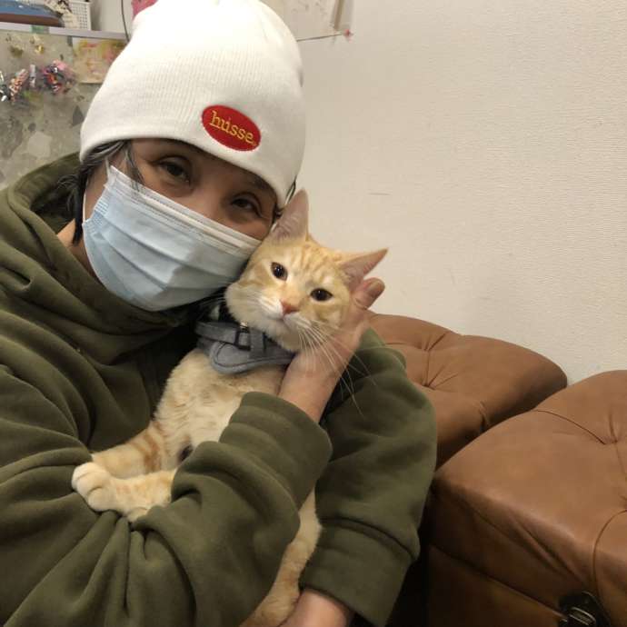 「保護猫カフェひだまり号」に在籍する猫を抱く女性