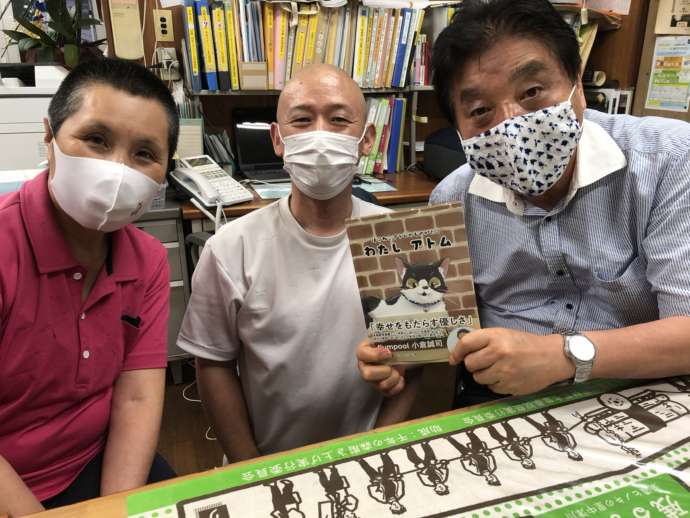 出版した本と一緒にほほ笑む「保護猫カフェひだまり号」の祖父江さんご夫妻と男性