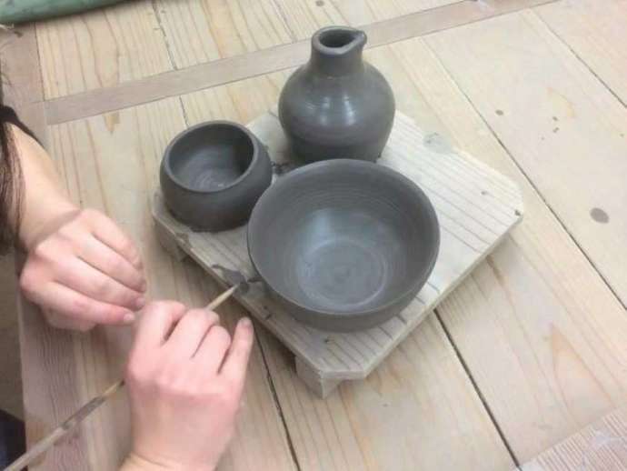 「備前焼窯元 宝山窯」での陶芸体験で名入れ作業をする様子