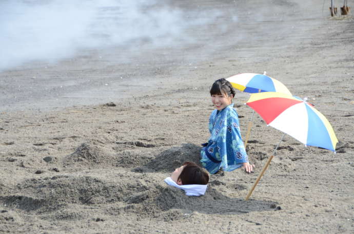 指宿市の海辺で砂むし体験をする女性二人