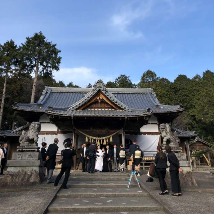 伊奈冨神社の拝殿前で記念写真を撮っている様子