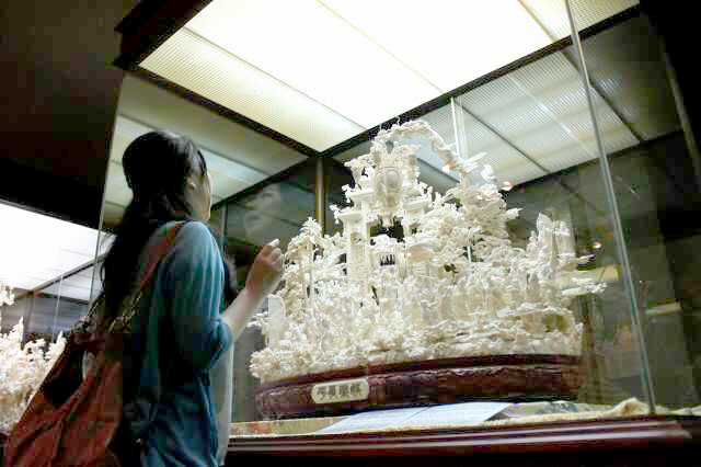 象牙と石の彫刻美術館の象牙彫刻「娯楽昇平」を見上げる女性