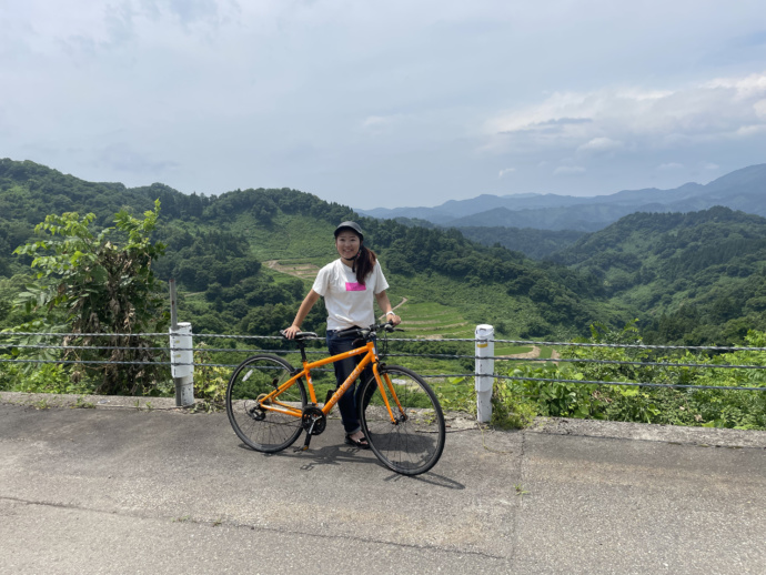 高柳の美しい田園風景をバックにポーズをとる自転車の女性