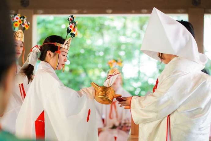 鎌倉宮の神前挙式で巫女が新婦の杯に御神酒を注ぐ様子