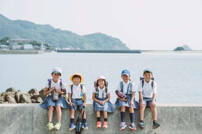 海を背に座って微笑む5人の小学生