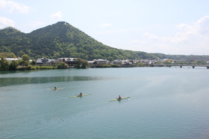 飛騨川でボートを漕ぐ人々と、背景に米田富士