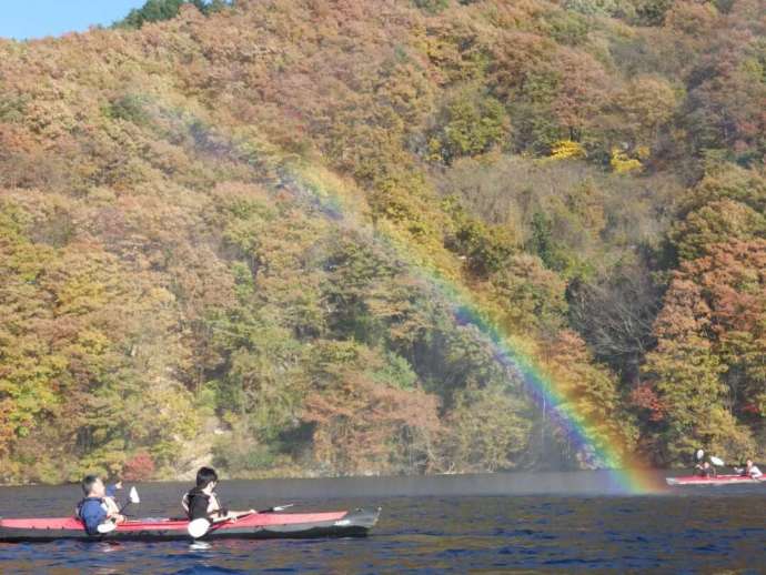 草木湖でカヌーを体験している方の向こう側に虹と山の風景が広がる