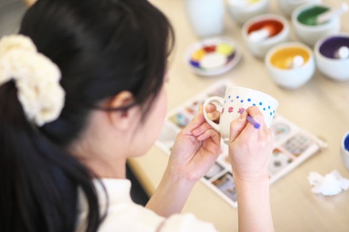 「九谷満月」の陶芸体験「絵付け体験コース」でカップに絵付け作業をする女性