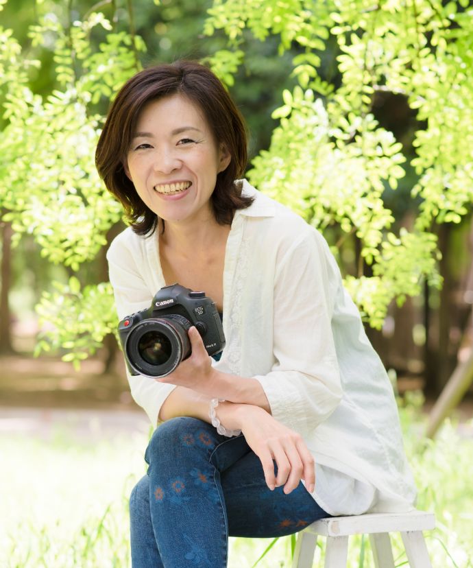 カメラを持って微笑む「Kyue Photo Works」のカメラマン久恵さん