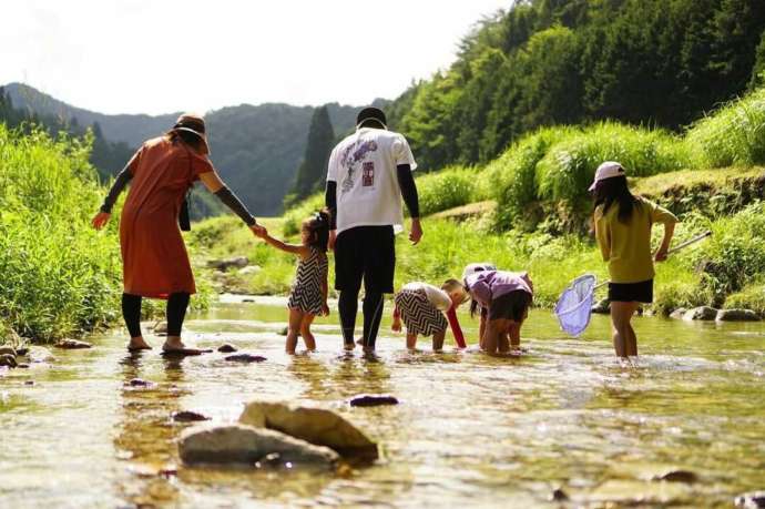 まるかりの里 久野川のキャンプ場周辺で水遊びをする人々