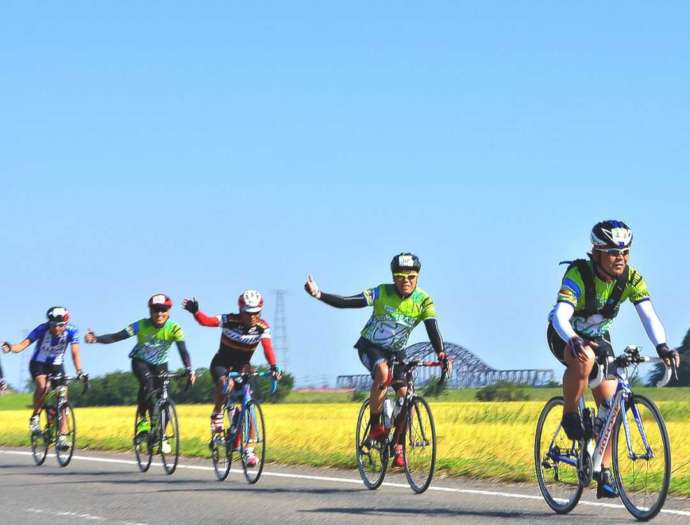 「サイクルフェスタ丸森」で、自転車に乗って田んぼの脇を走行する人々