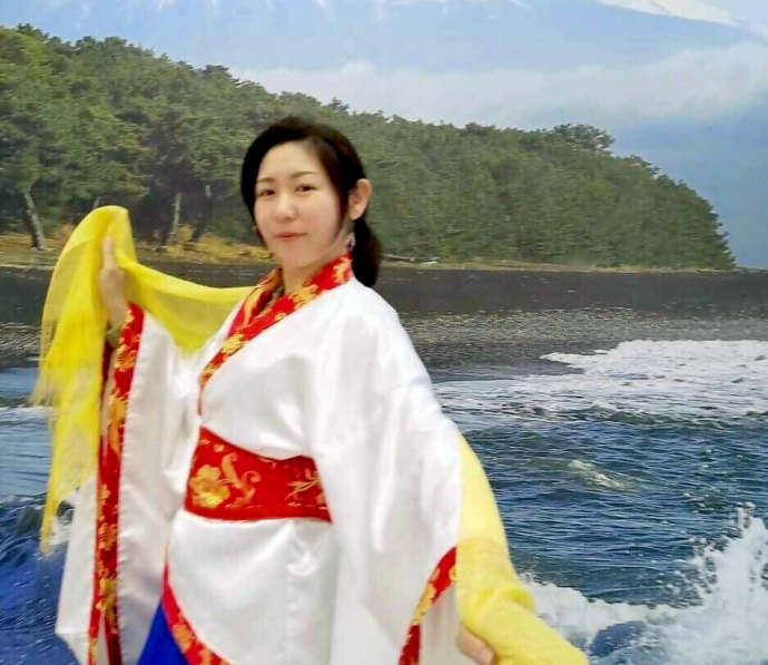 富士山の写真パネルの前で天女の衣装を着て記念撮影している女性