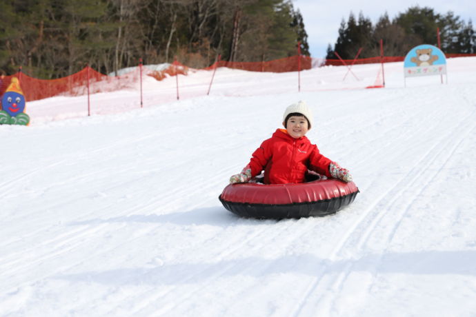 スキー場でソリ滑りをする子ども