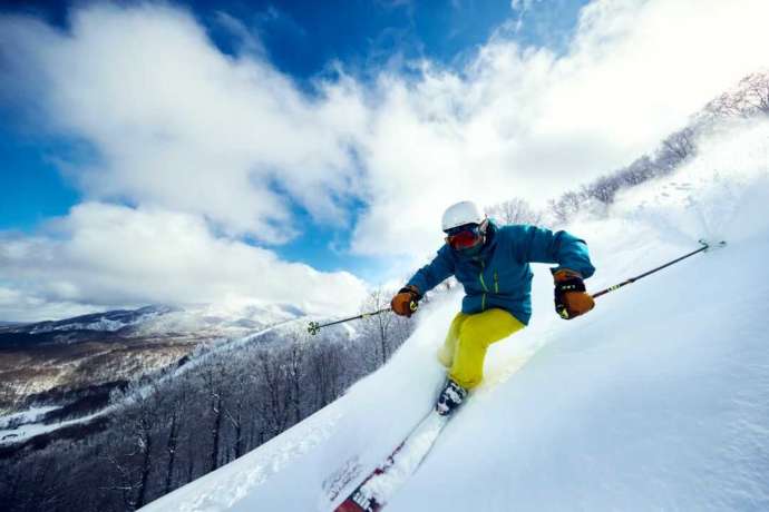 「星野リゾート 猫魔スキー場」の上質なパウダースノーの斜面を滑り降りるスキーヤー