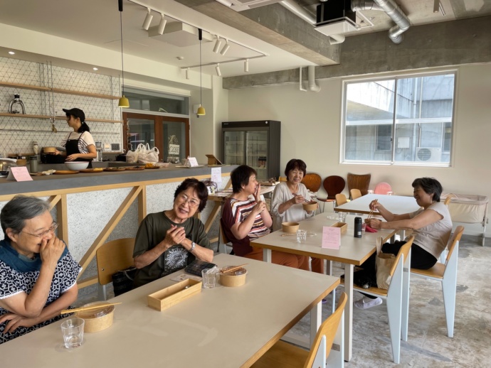 「UECHUカフェ」で食事をする人々