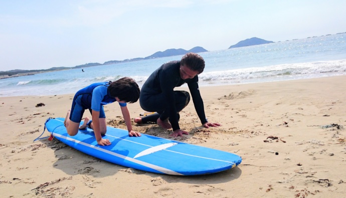 福岡県岡垣町の波津海岸で小学生向けのサーフィン教室を行っている様子