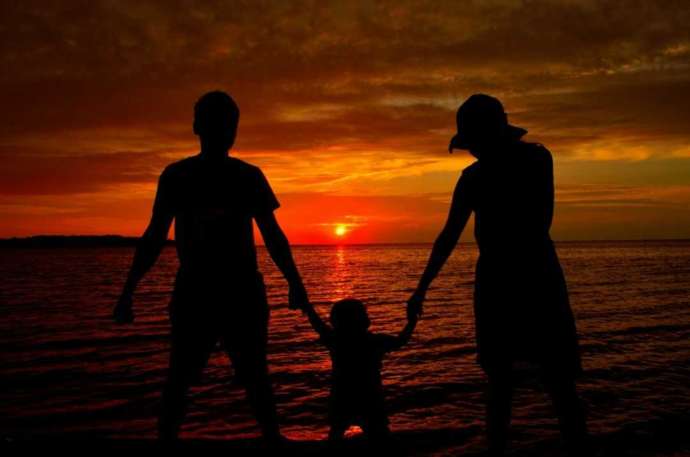海に沈む夕日を眺めている家族