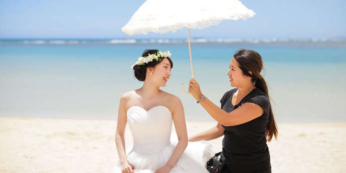 撮影の間に日傘を花嫁さんにかざすスタッフ