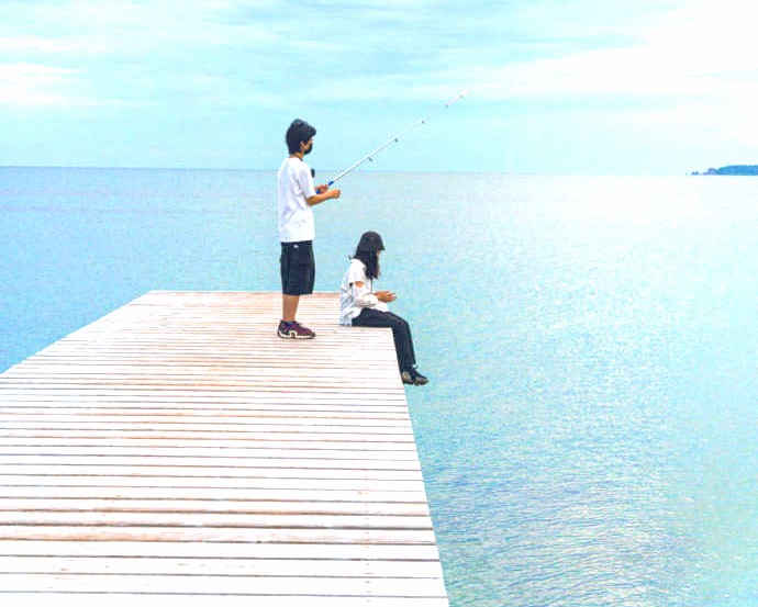 あめやの桟橋で釣りをする男性と座る女性
