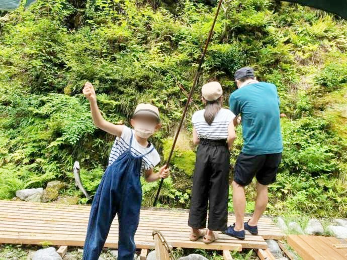 「渓流魚料理のお店 醒井楼」前の渓流でニジマスを釣り上げた子供とご両親