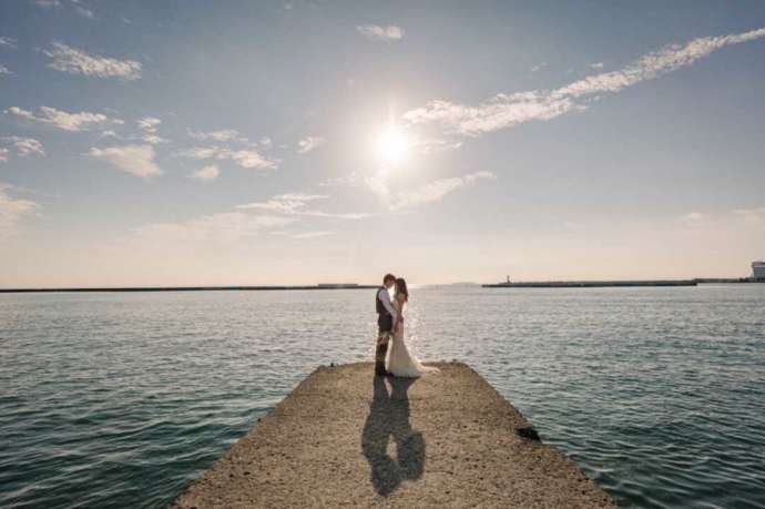 海に突き出した桟橋でロケーション撮影している新郎新婦