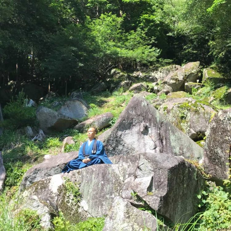 山梨県甲州市の栖雲寺内の荒々しい岩の上で坐禅をする様子