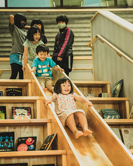 椎葉村交流拠点施設「Katerie」にある図書館のすべり台で遊ぶ子どもたちの写真