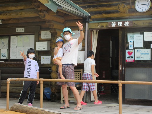 真道山森林公園キャンプ場の管理棟前で写真撮影をする家族
