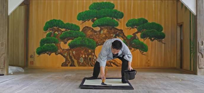 板間で墨書する「JAPANESE BRUSH DESIGN WORKS Kaku」代表で書家の角谷さん