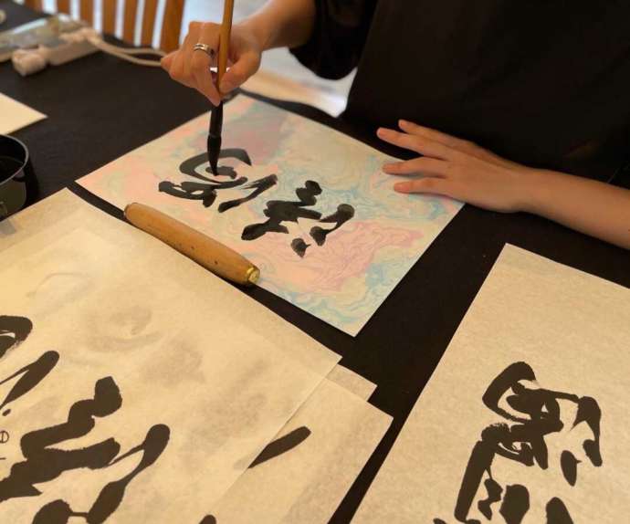「JAPANESE BRUSH DESIGN WORKS Kaku」で墨流しで染めた越前和紙に清書中