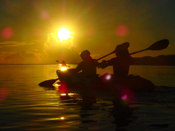 沖縄県石垣市にある「石垣島シュノーケルツアー」で夕日に照らされながらカヤックを漕ぐ二人