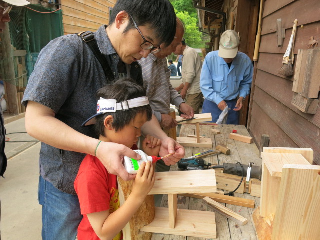 子どもと大人が一緒に木工作品を作っている様子