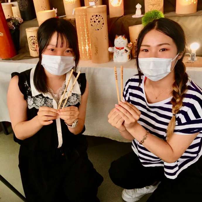 「竹灯籠工房」の体験教室で制作した竹箸の完成例と参加した女性2名