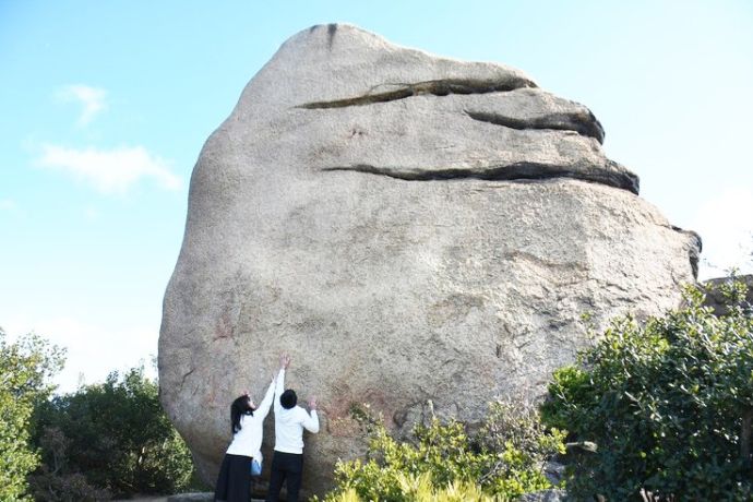 ニコニコ岩で記念撮影を楽しむカップル
