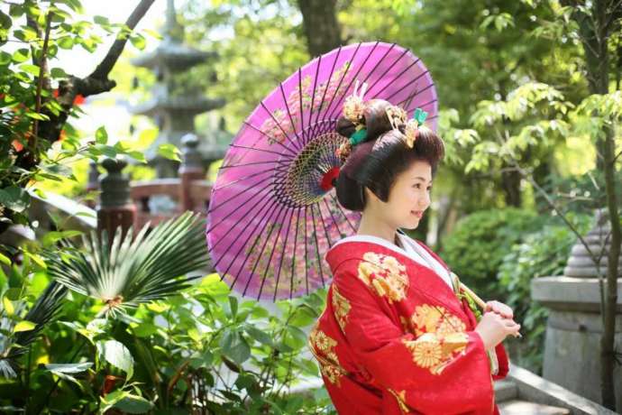 讃岐國一宮田村神社の境内で番傘をさす赤い打掛の新婦