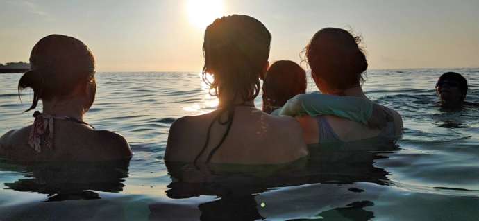 子どもと一緒に海で泳ぐ女性たち