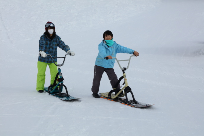 白馬つがいけ高原スキー場のSNOW WOW !エリアでスノーモトという乗り物に乗る2人の子供の写真