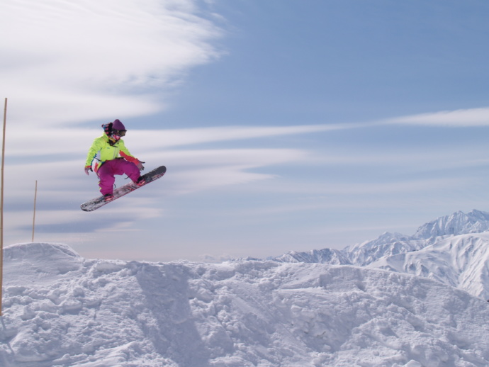 白馬つがいけ高原スキー場のゲレンデでジャンプするスノーボーダー